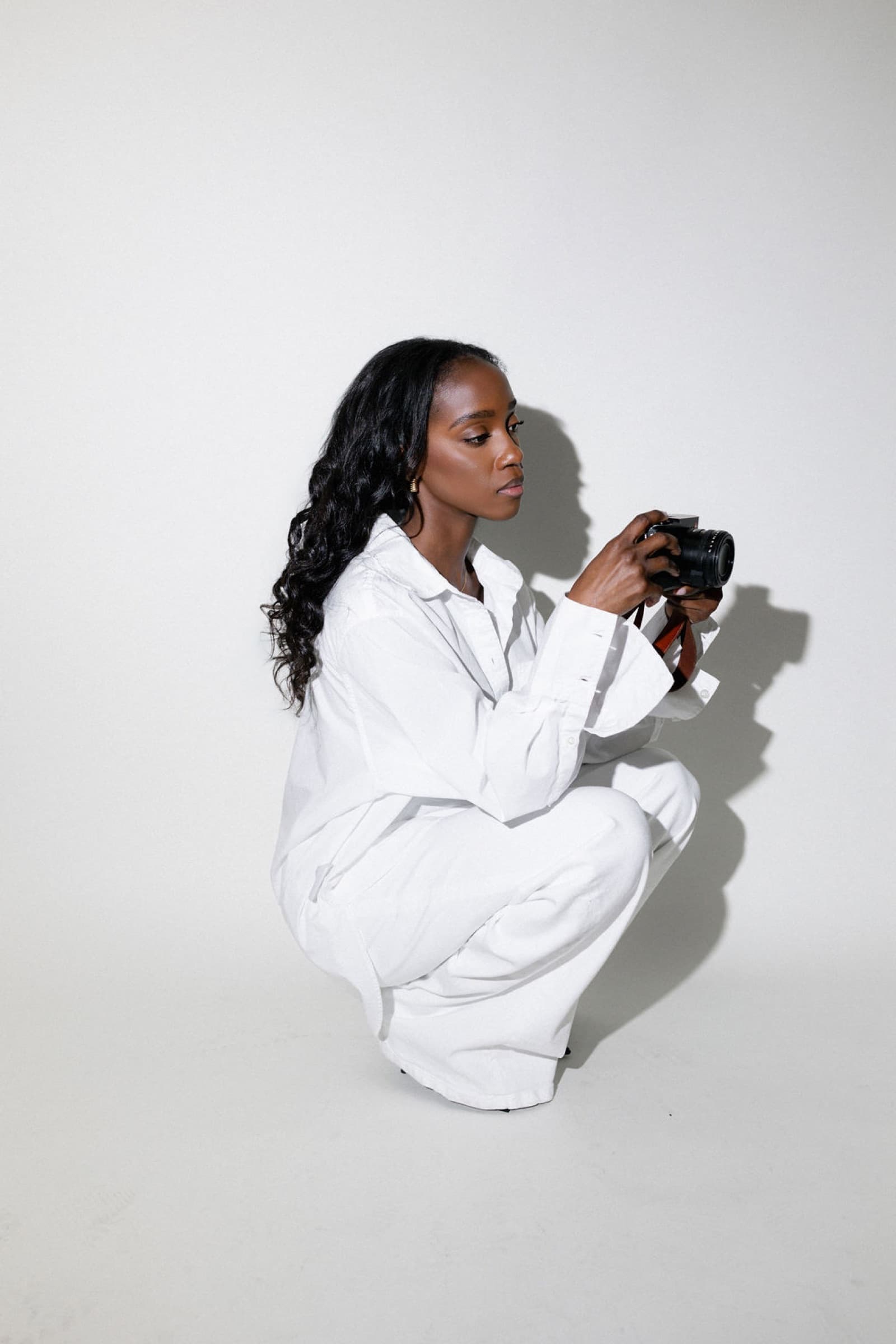 Judea crouching with her camera in a studio shoot