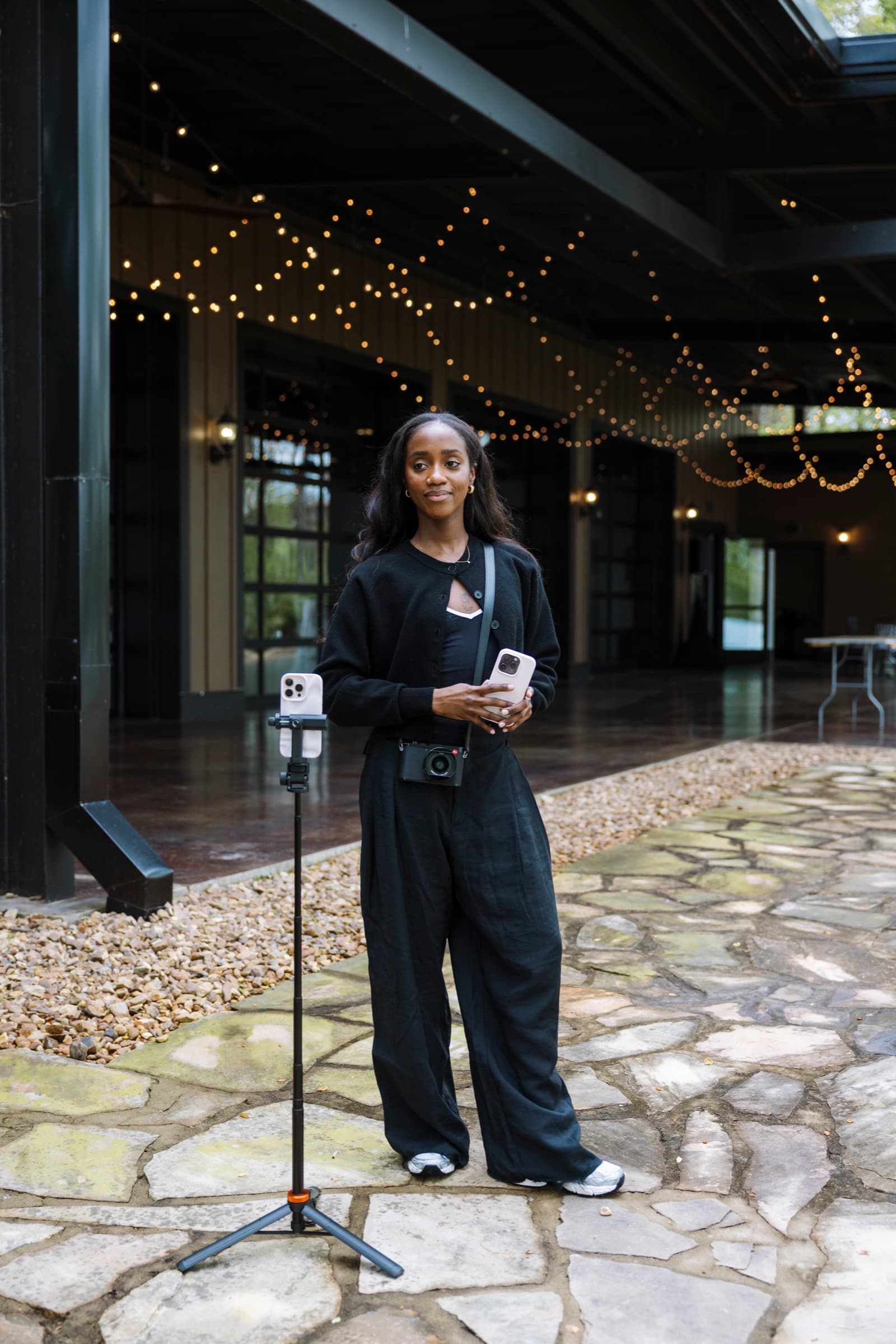 Judea with her phone gimbal under string lights at a wedding venue